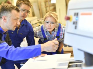 Professional teacher showing carpentry machinery to students