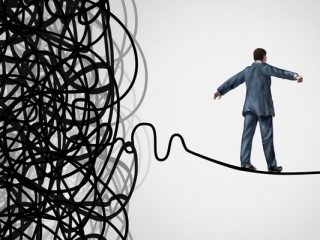 Crisis Management business concept as a tightrope walker walking out of a confused tangled chaos of wires breaking free to a clear path of risk opportunity as a metaphor for managing organizational challenges for financial freedom and success.