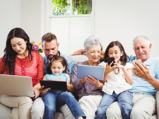Happy family using technologies while sitting on sofa at home