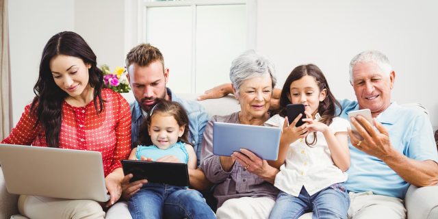 Happy family using technologies while sitting on sofa at home